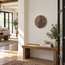 Round palm tree stone mosaic wall art on wall above a console