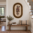 Oval stone mosaic wall art with Greek key border and floral bird motif in warm tones