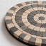 Stone mosaic coaster edge with black and beige square tiles forming concentric circle design