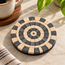 Round stone mosaic coaster featuring concentric black and tan tile rings with center rosette