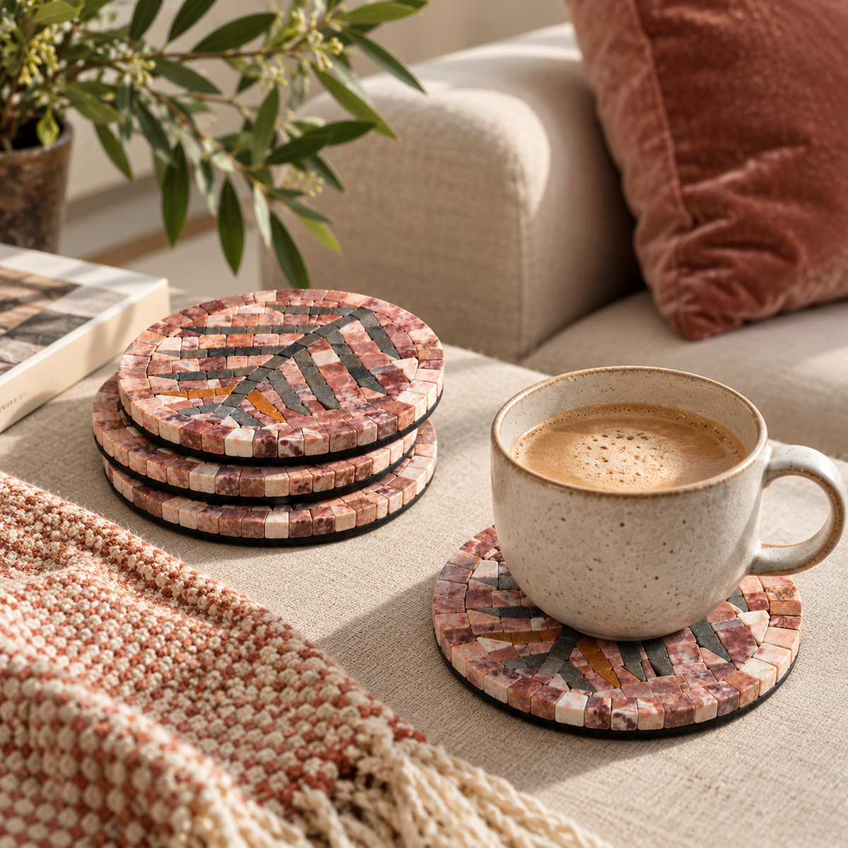 Round stone mosaic coaster with pink, beige and dark geometric pattern, under a mug