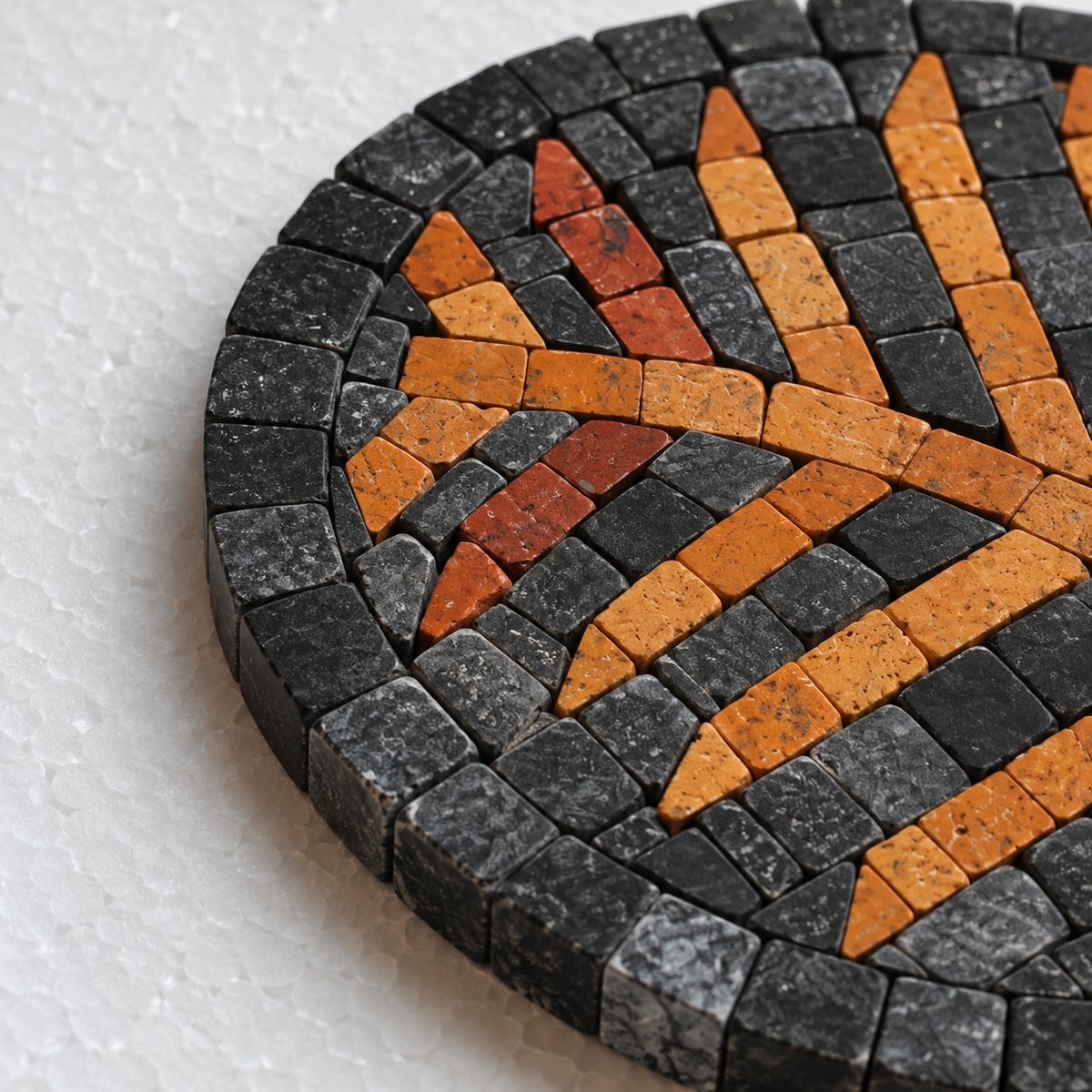 Round black stone mosaic coaster with amber and red radial stripe detail