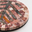 Close-up of round stone mosaic coaster edge with pink, beige, and dark tile sections