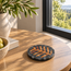 Round stone mosaic coaster with black border and amber radial leaf motif