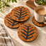 Set of round stone mosaic coasters with orange tiles and black tree-branch patterns