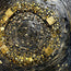 Gold and black stone mosaic wall art with circular swirl pattern, close-up detail