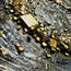 Stone mosaic swirl wall art with gold and beige tile fragments on dark surface