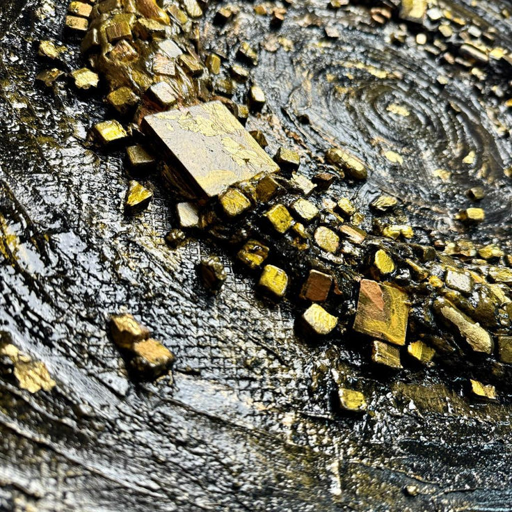 Stone mosaic swirl wall art with gold and beige tile fragments on dark surface