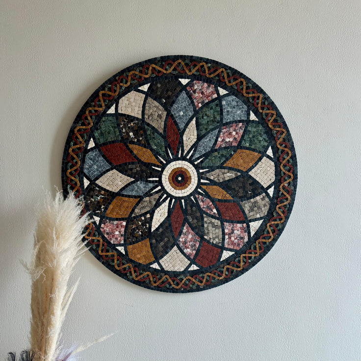 Round stone mosaic floral rosette wall art with multicolor tiles; feather decor at bottom left